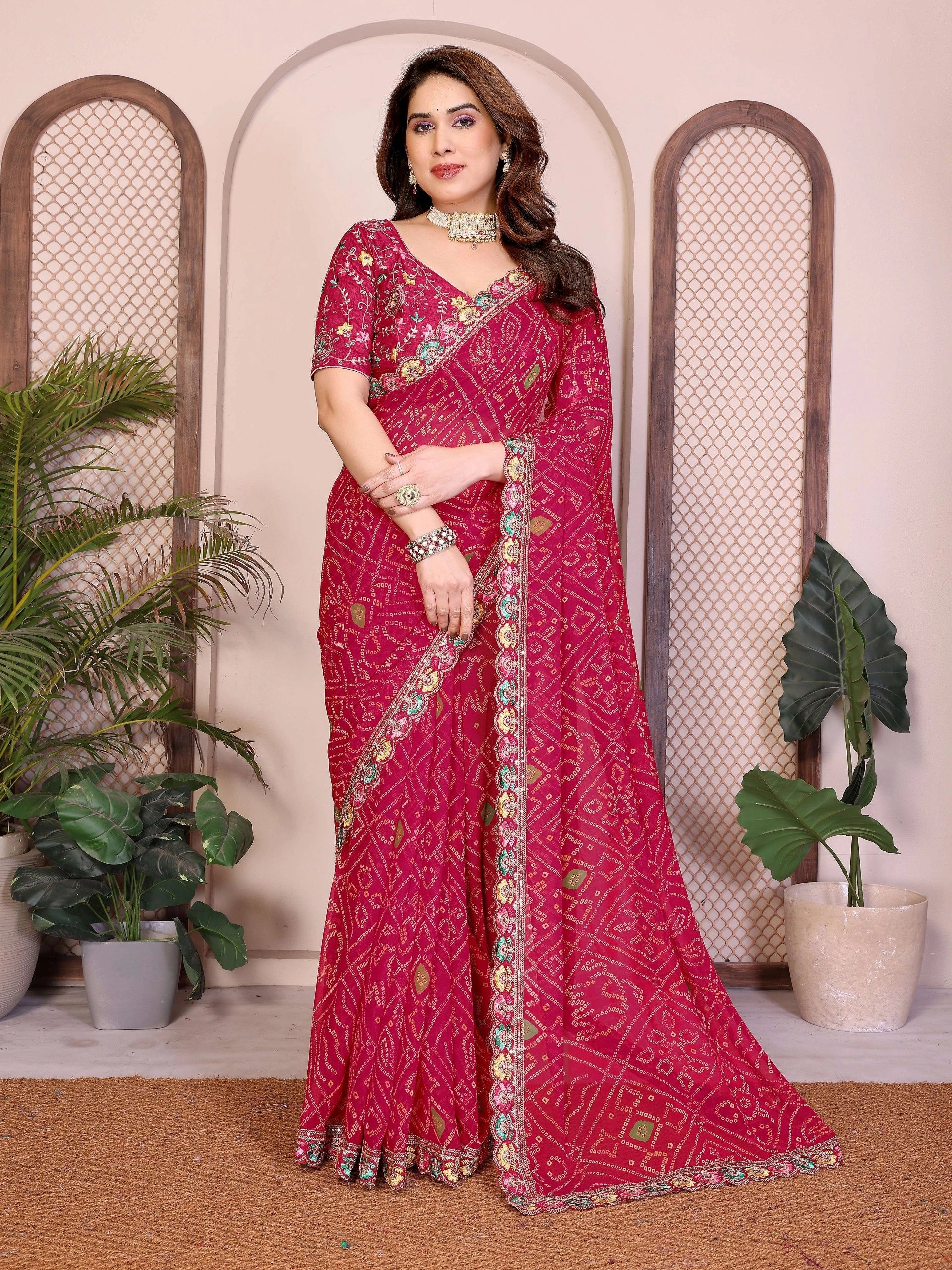 Woman wearing a pink saree with a decorative border in a room with plants.