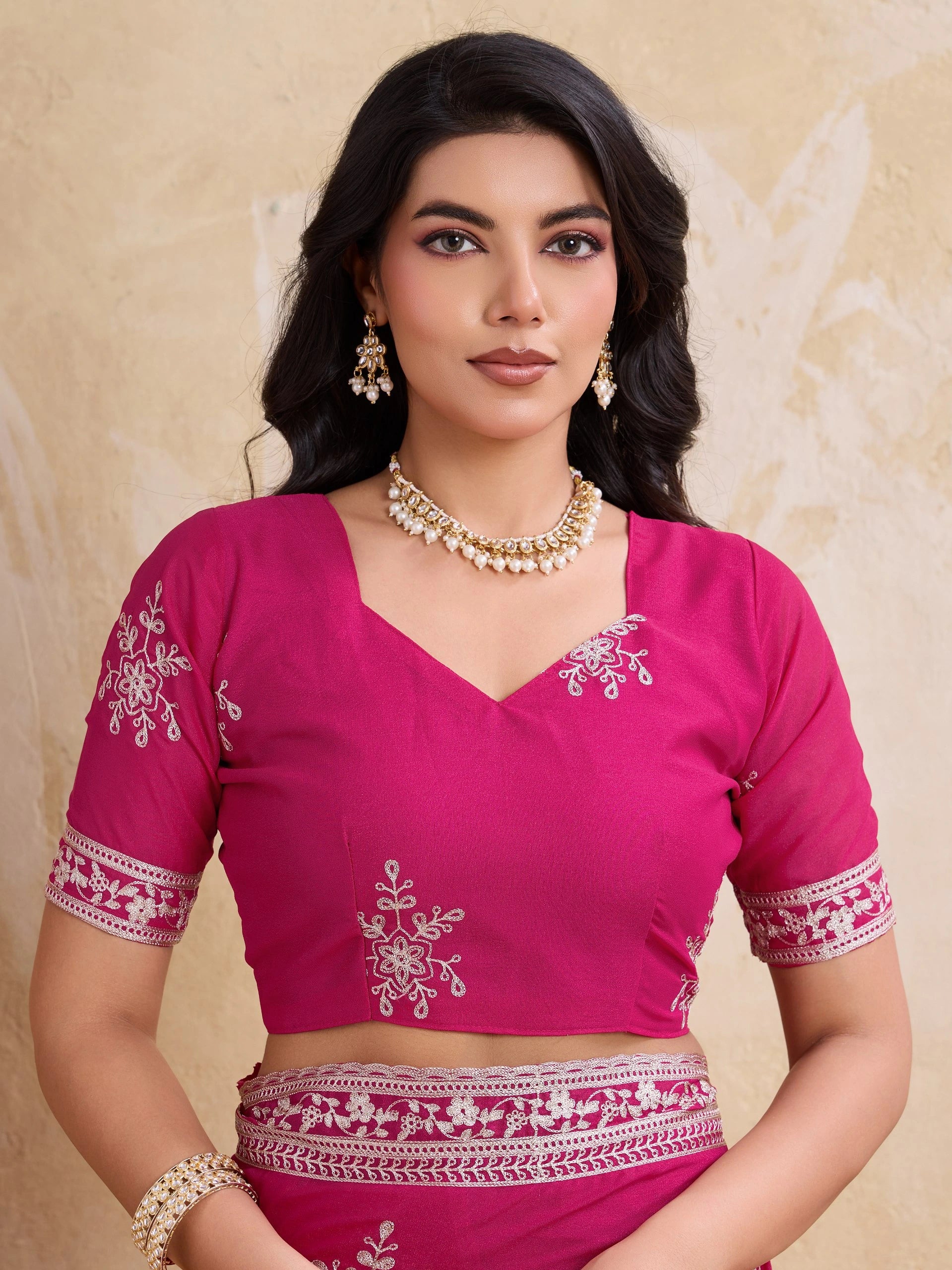 Woman wearing a pink blouse with white embroidery on a beige background