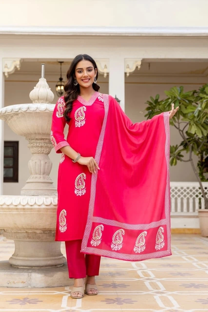 Woman in a pink traditional outfit with a matching dupatta, standing outdoors.
