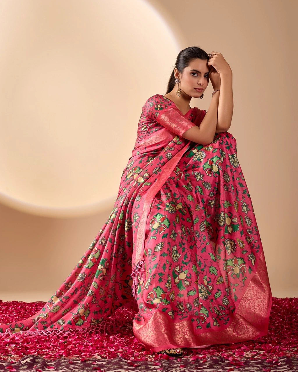 Woman wearing a pink saree with floral patterns on a beige background