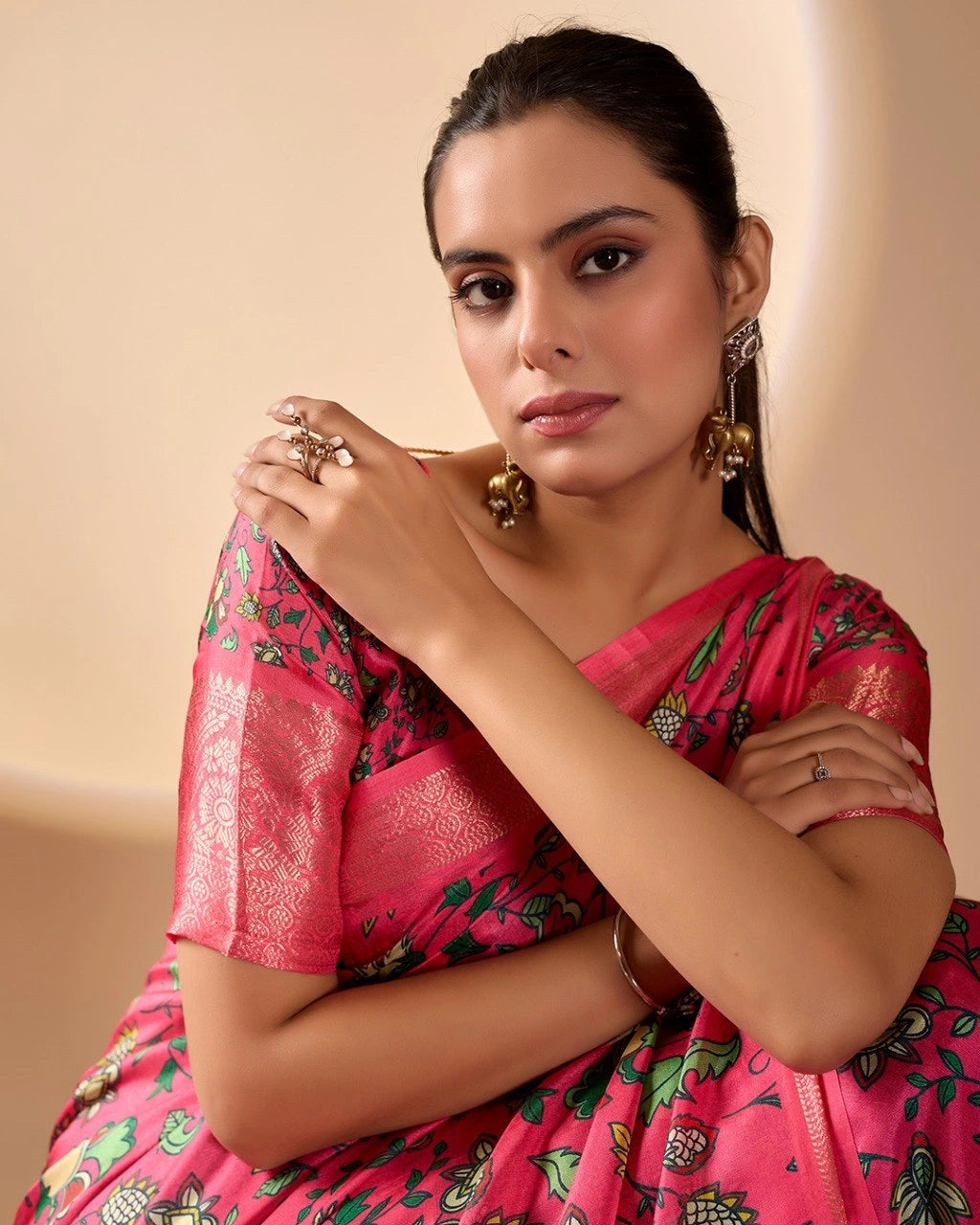 Woman wearing a pink saree with floral patterns on a beige background