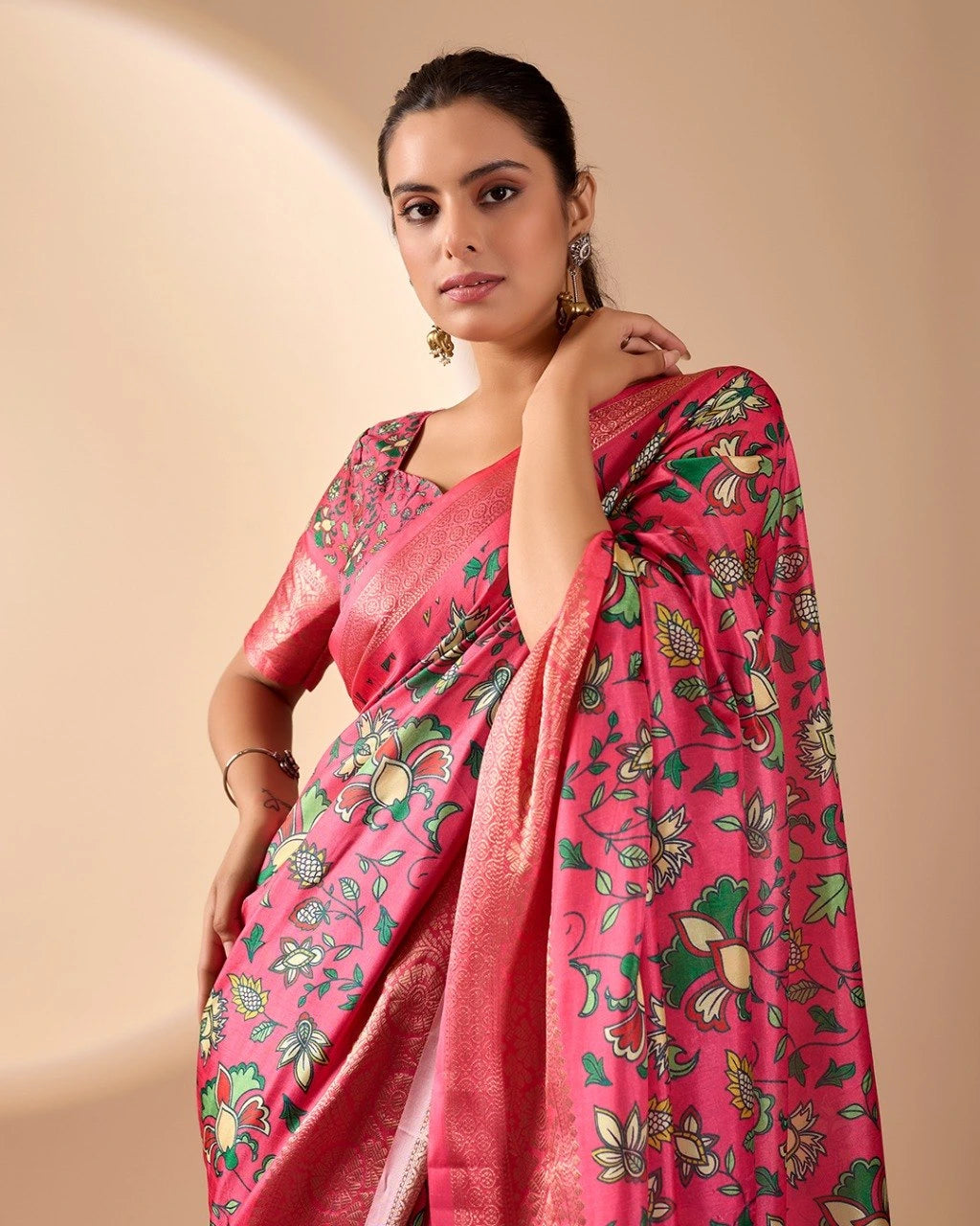 Woman wearing a pink saree with floral patterns on a beige background