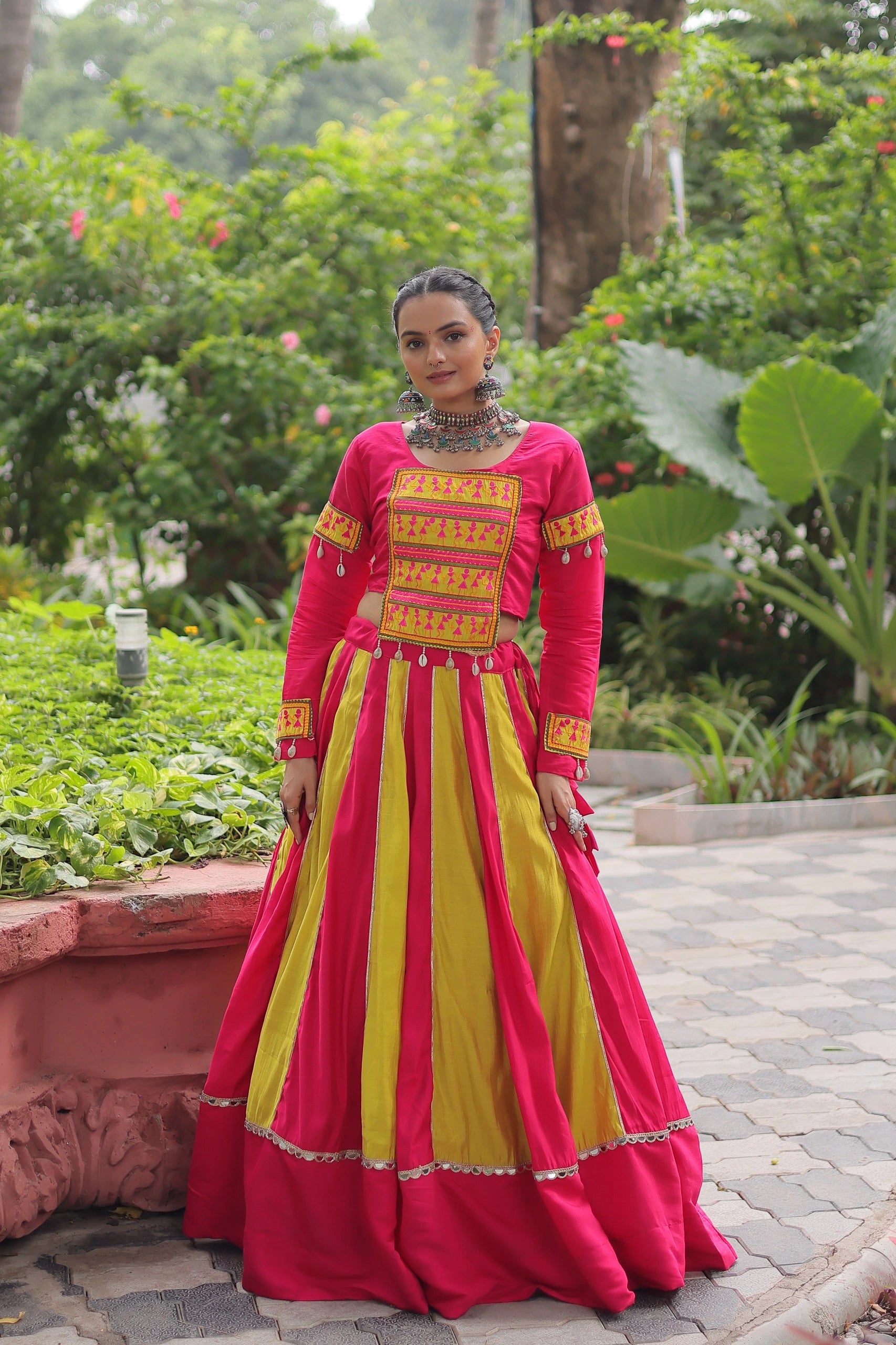 Woman in a red and yellow traditional outfit standing in a garden.