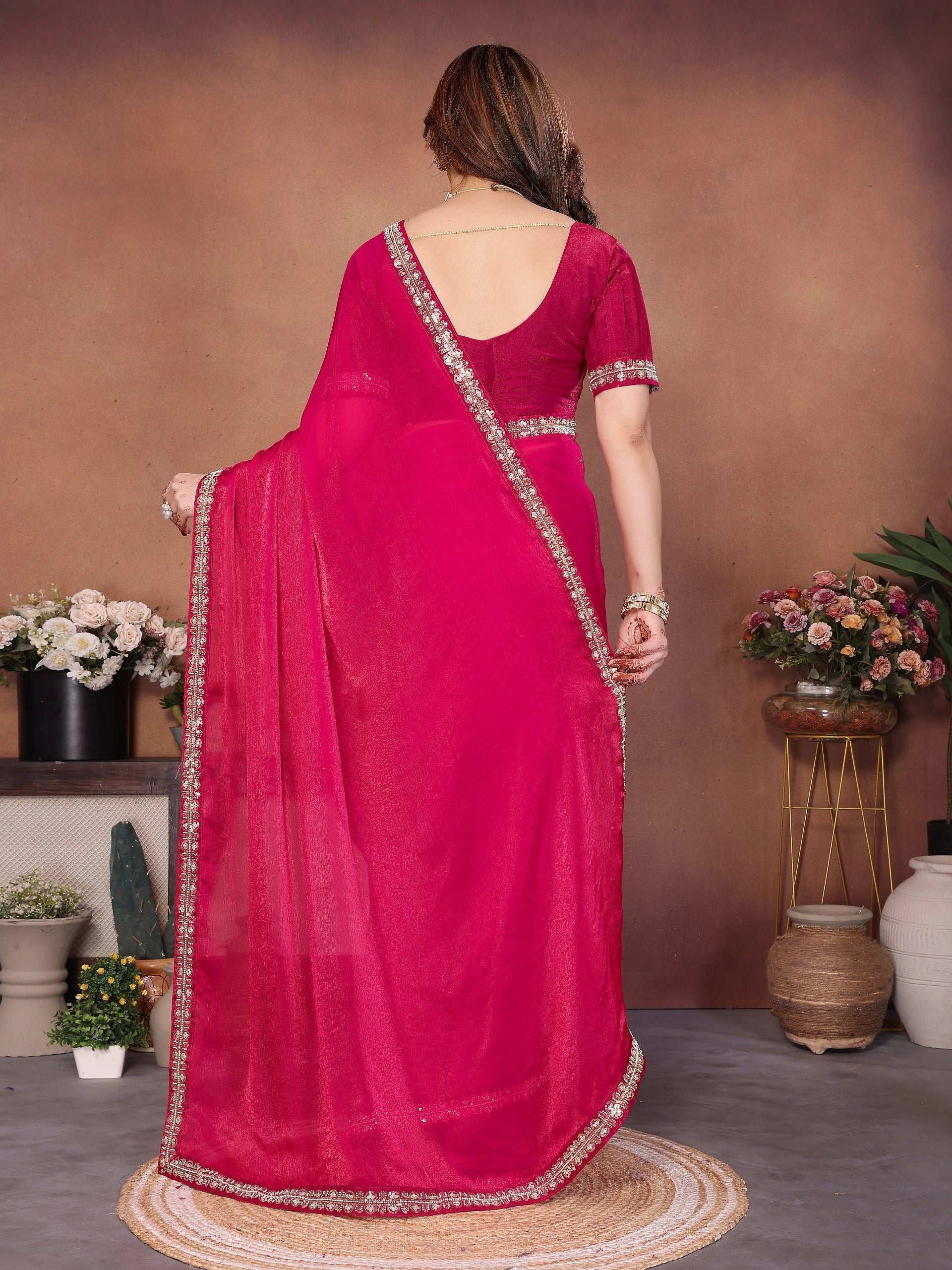 Woman wearing a pink saree with a plain background