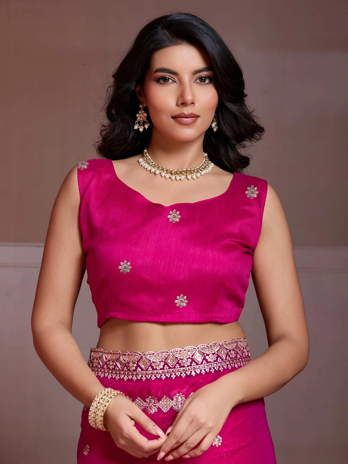 Woman wearing a pink traditional outfit with intricate designs on a plain background