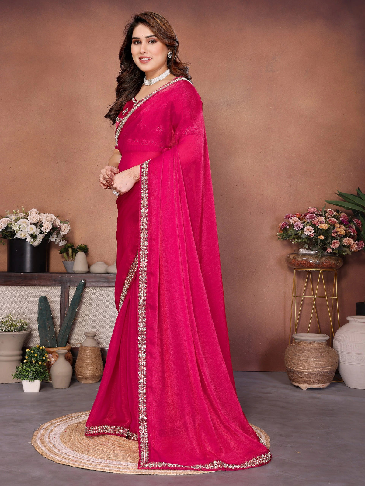 Woman in a bright pink saree with a brown background