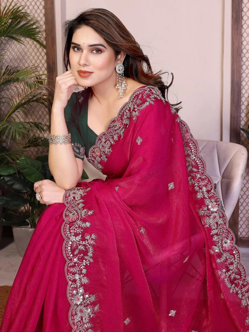 Woman wearing a pink saree with silver embroidery indoors.