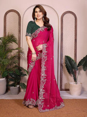 Woman wearing a pink saree with green blouse in an indoor setting with plants.
