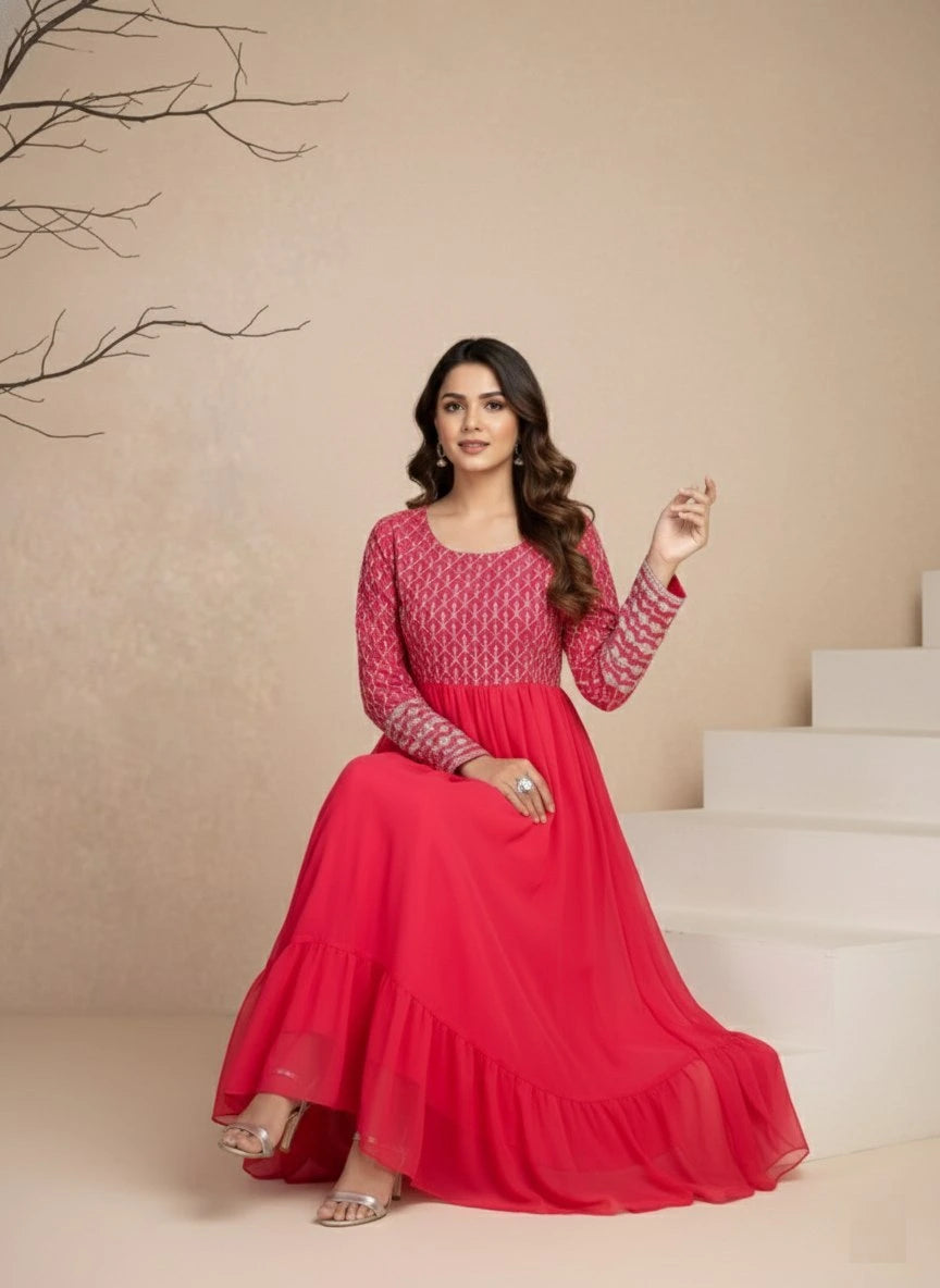 Woman in a red and pink traditional outfit sitting on stairs with a neutral background