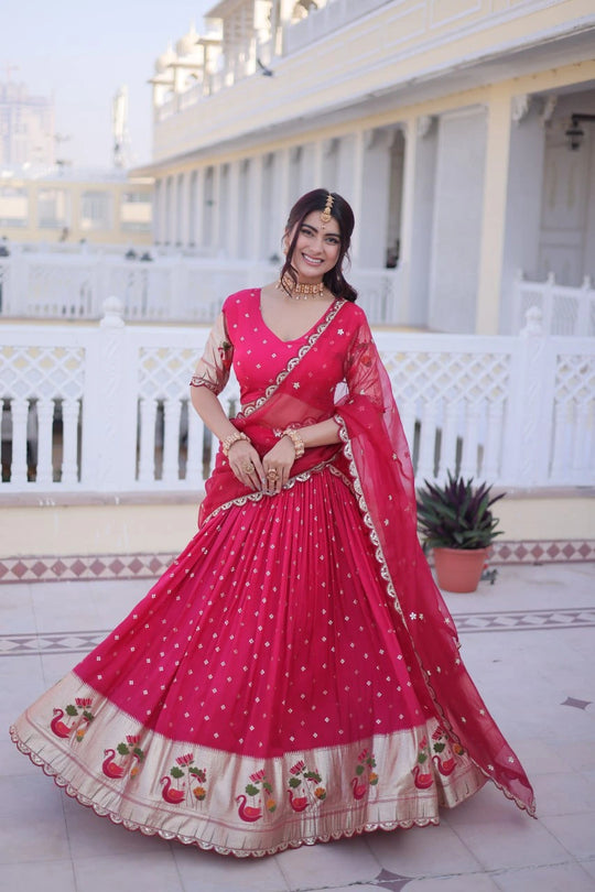Woman in a pink traditional outfit standing in front of a white building.