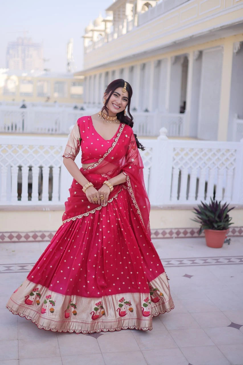 Woman in a red traditional outfit standing on a balcony with white columns and a plant in the background.