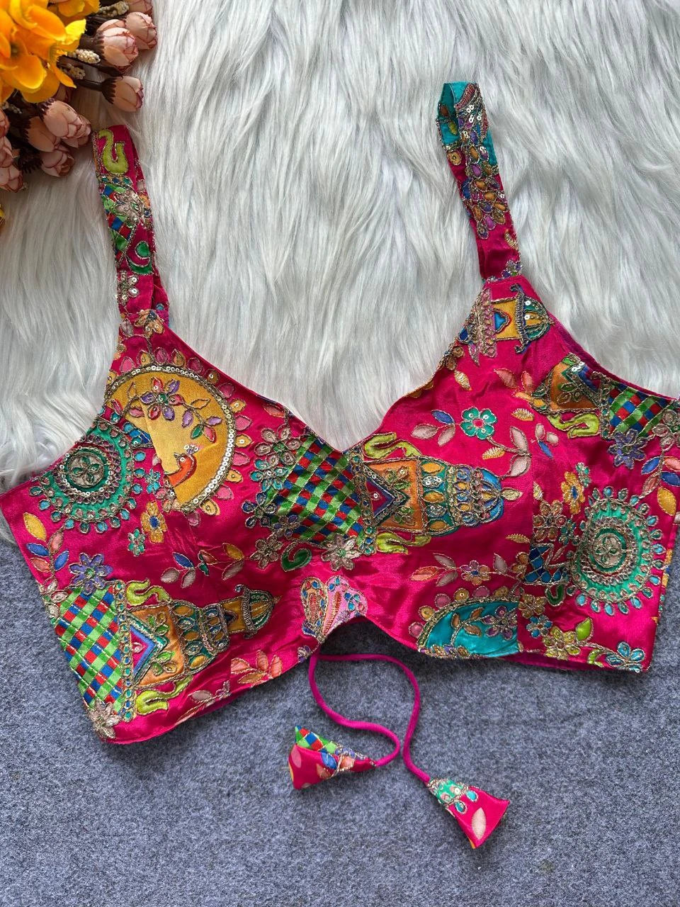 Colorful embroidered pink blouse with floral patterns on a textured surface