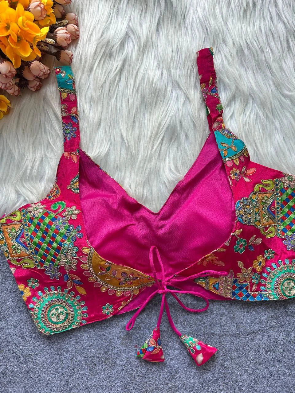 Pink embroidered top with colorful patterns on a textured surface