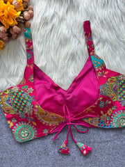 Pink embroidered top with colorful patterns on a textured surface