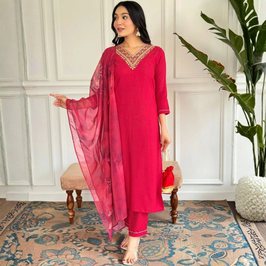 Woman in a pink traditional outfit standing in a room with decorative elements.