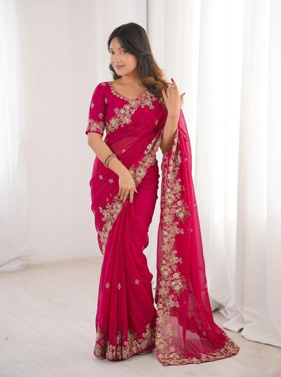 Woman wearing a pink saree with gold embroidery against a white curtain background