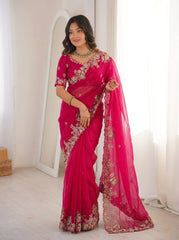 Woman wearing a bright pink saree with gold embroidery in a room.