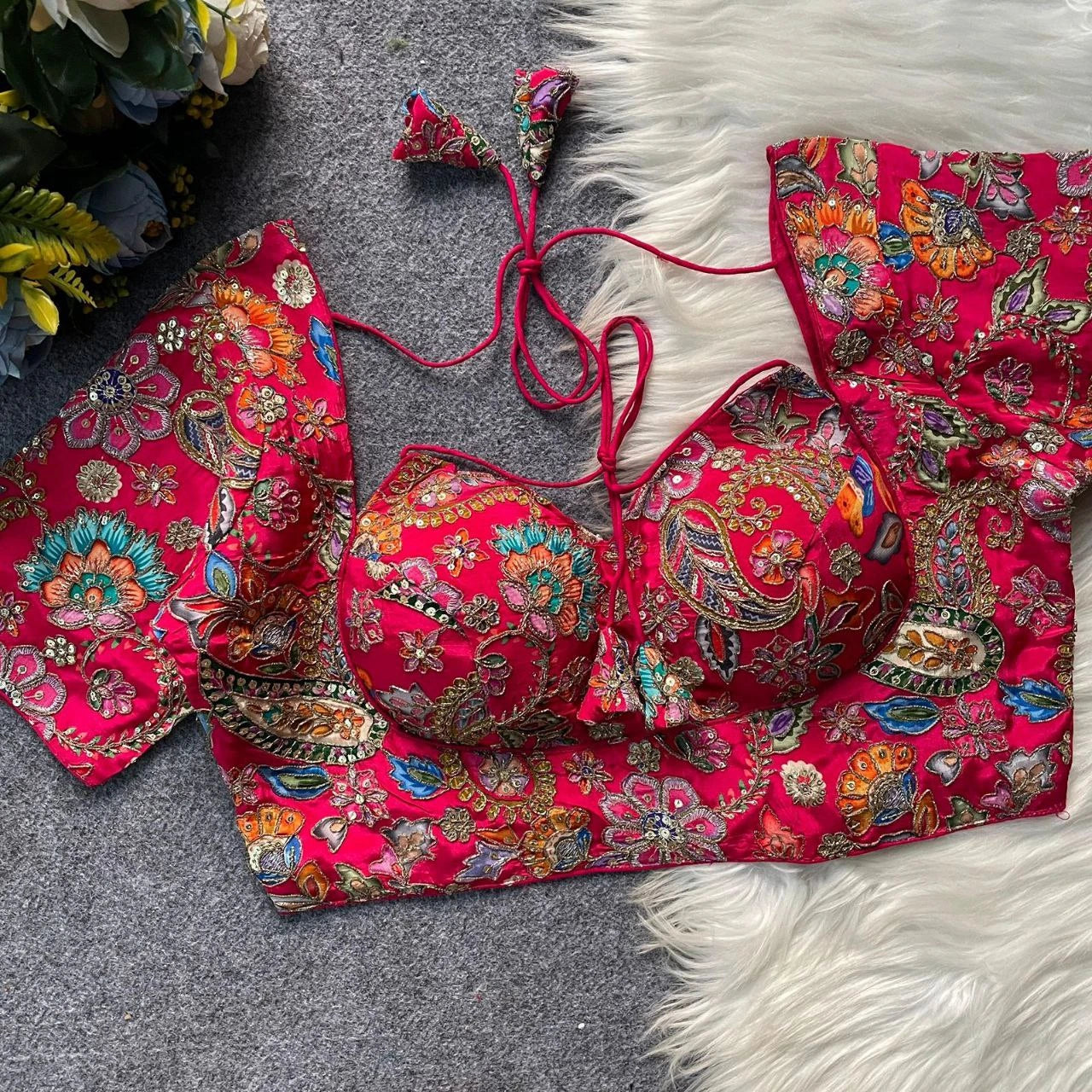 Red embroidered bikini set on a textured surface with floral patterns.