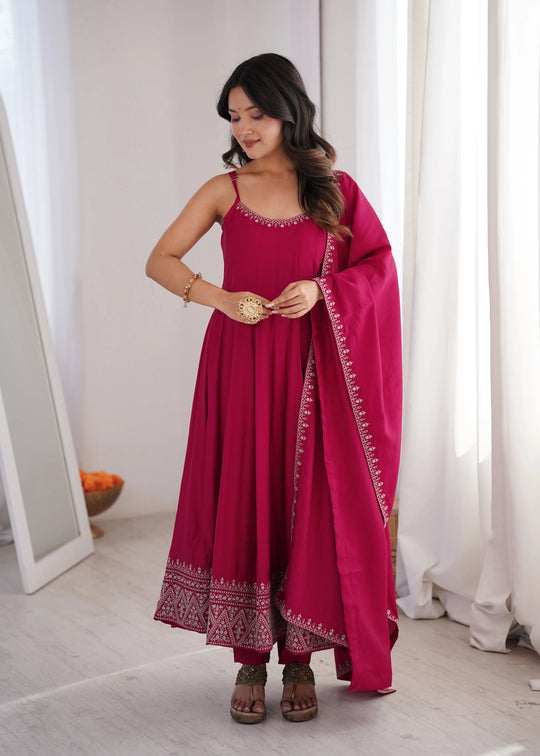Woman wearing a pink traditional outfit with a matching dupatta indoors.