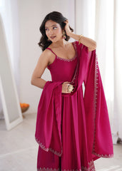 Woman in a pink traditional outfit with a matching dupatta, standing indoors.