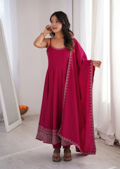 Woman in a pink traditional outfit standing in a room with white walls and a mirror.