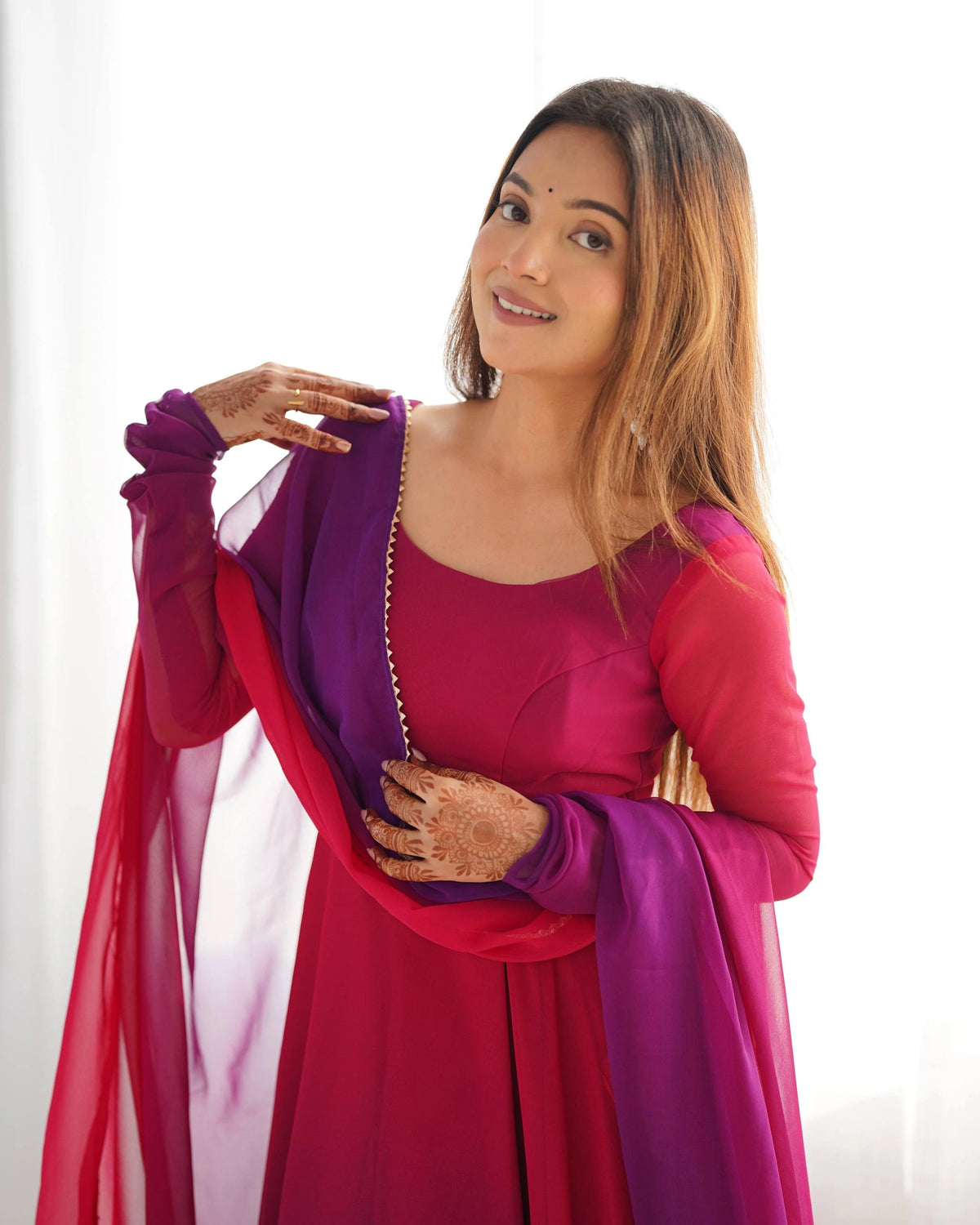 Woman wearing a pink and purple traditional outfit with a white background