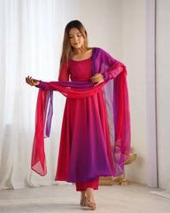 Woman wearing a pink and purple traditional outfit with a scarf in a bright room.