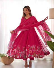Woman in a pink floral dress with a matching dupatta in a bright room.