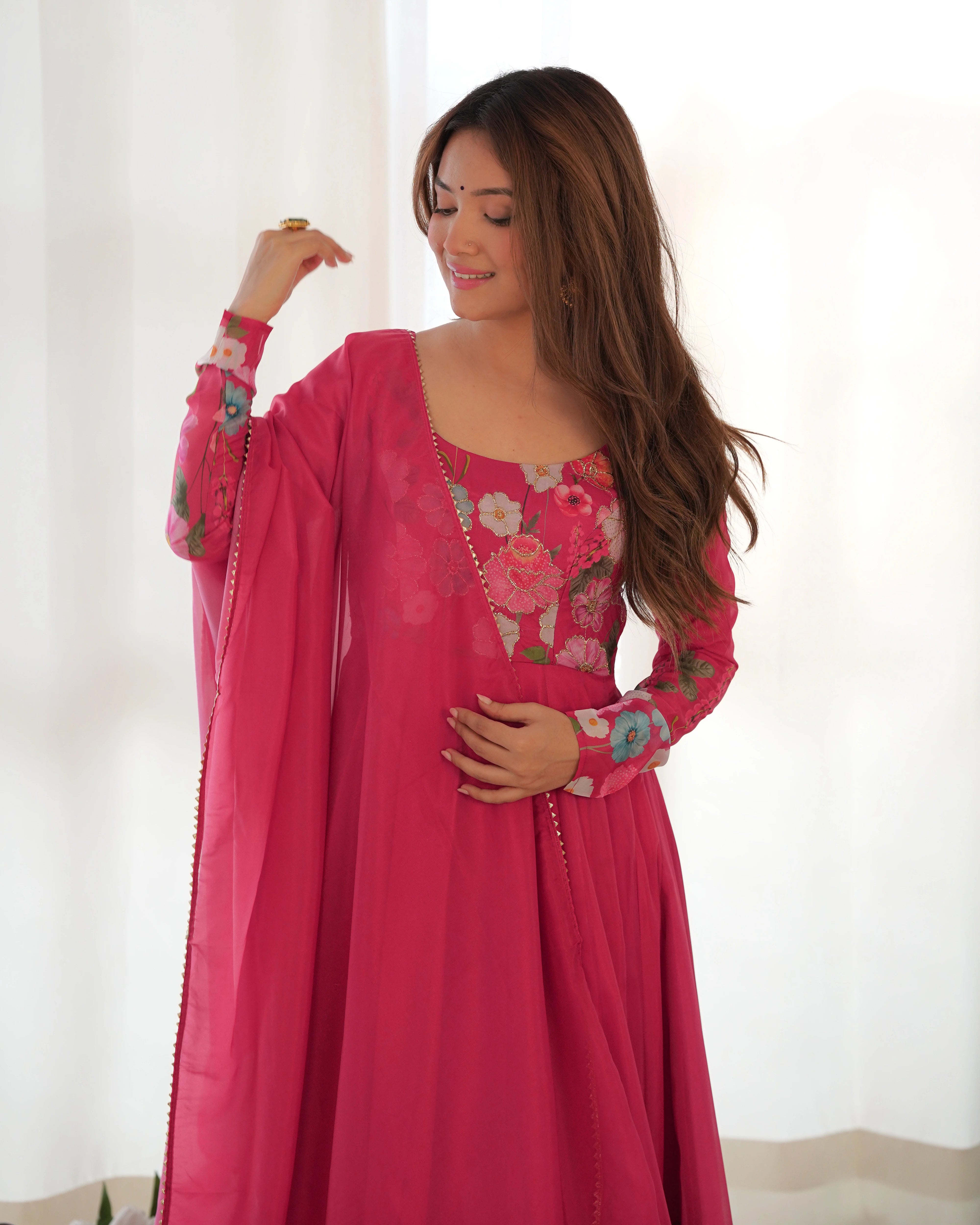 Woman wearing a pink embroidered dress against a white background