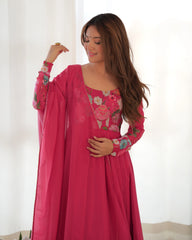 Woman wearing a pink embroidered dress against a white background