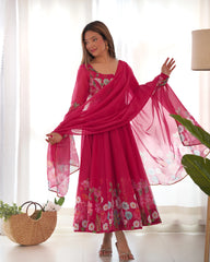 Woman in a pink floral dress with a matching dupatta in a bright room.