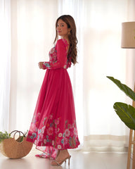 Woman wearing a pink floral dress standing in a bright room with white curtains.