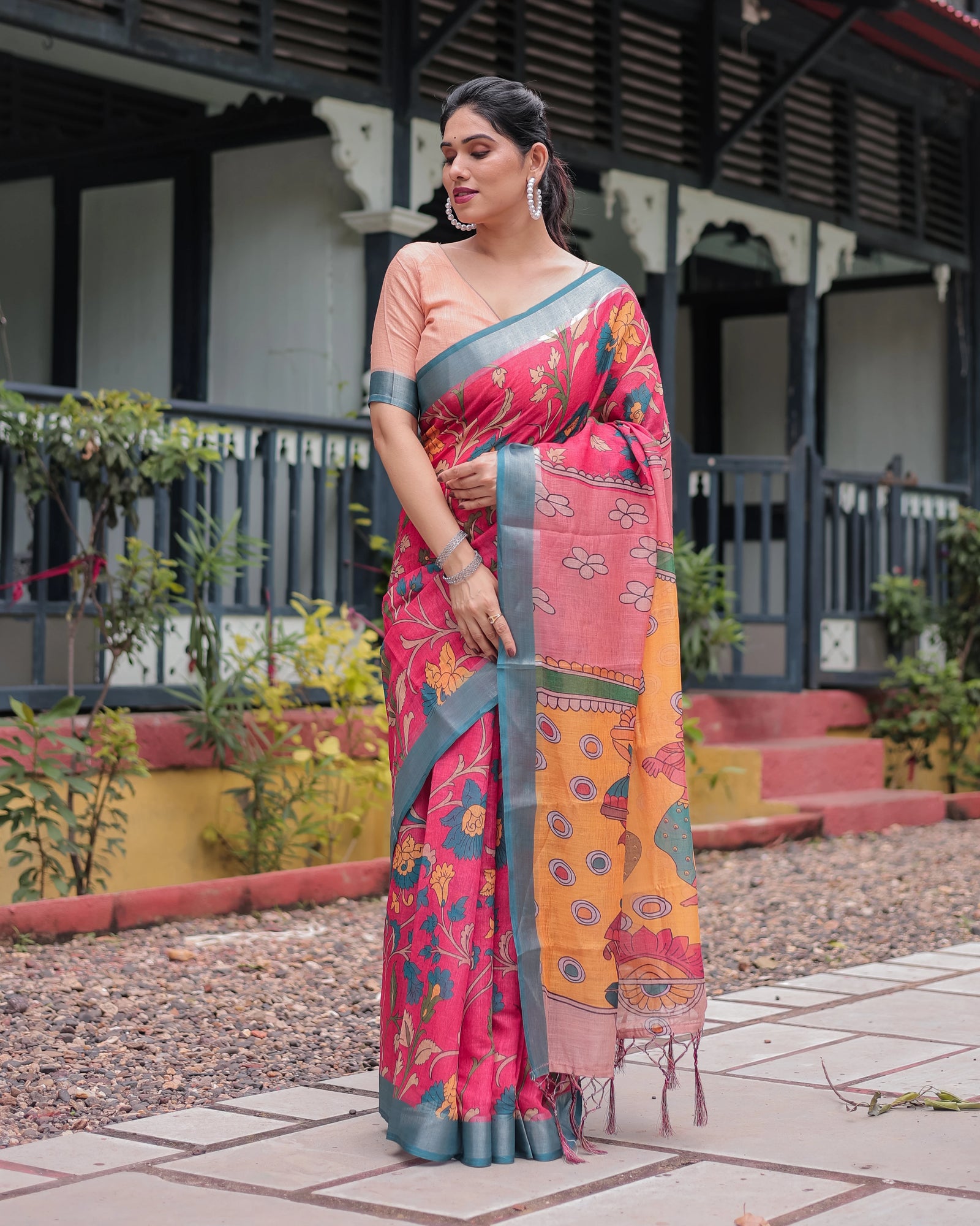 Woman wearing a colorful saree standing outdoors with a traditional building in the background