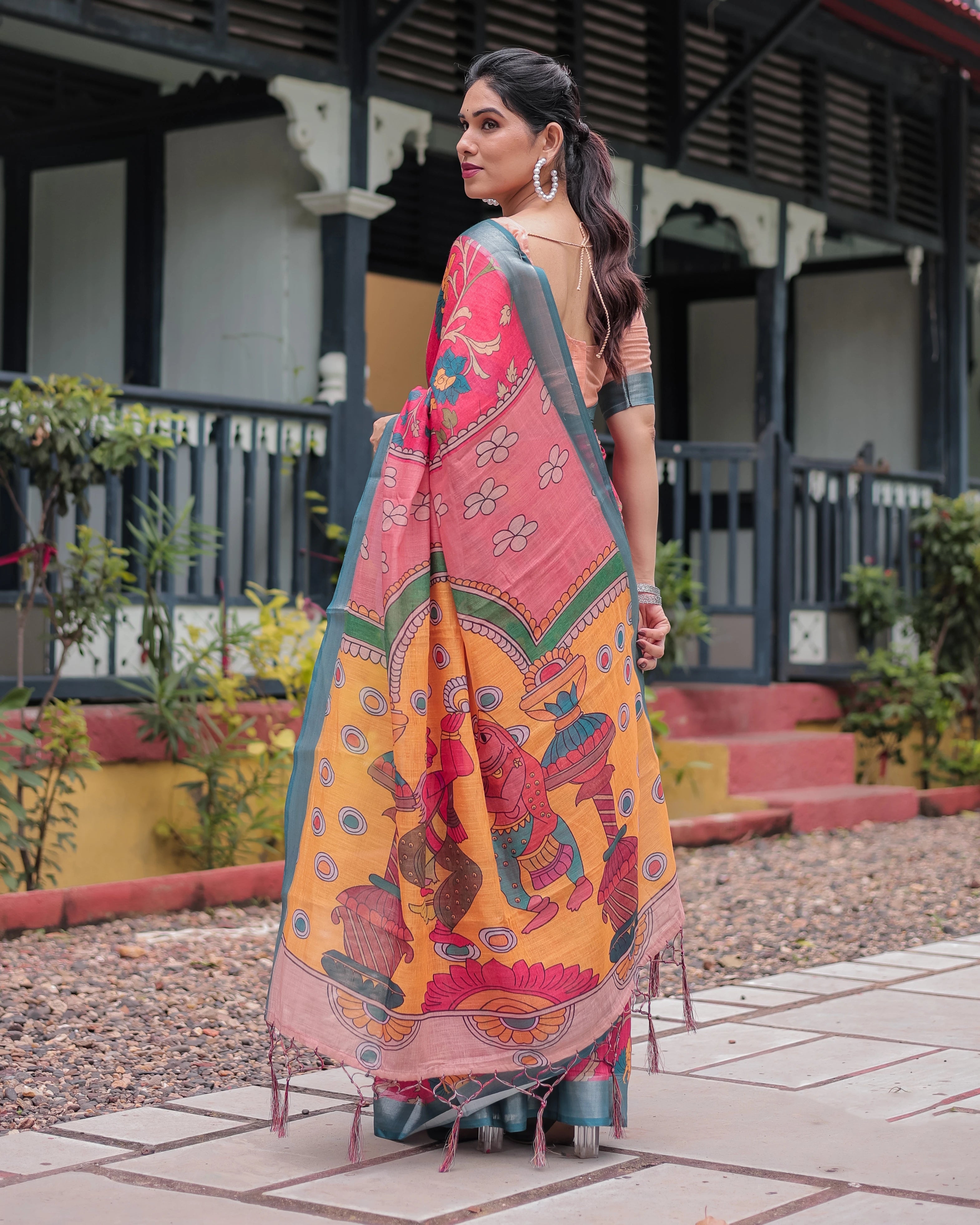 Woman wearing a colorful saree with a traditional design outdoors.