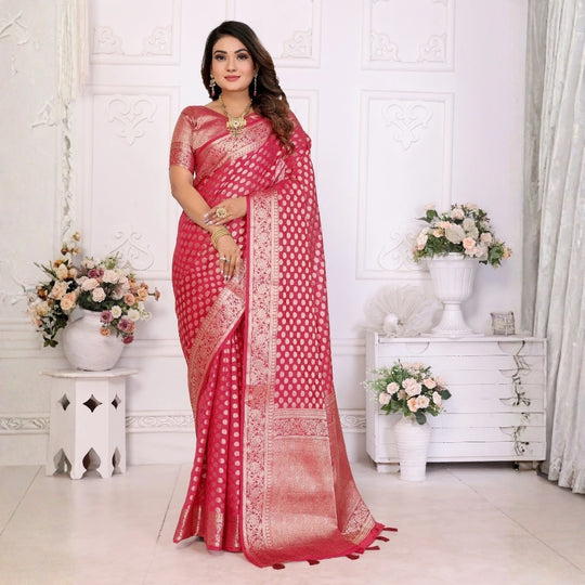 Woman wearing a red saree with white patterns in a decorated room.