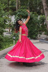 Woman in a bright pink traditional outfit dancing outdoors.