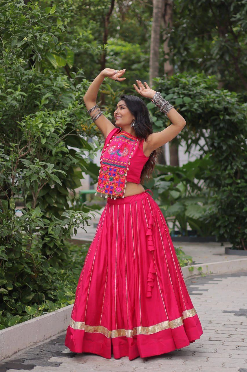 Woman in a bright pink traditional outfit with colorful top dancing outdoors.