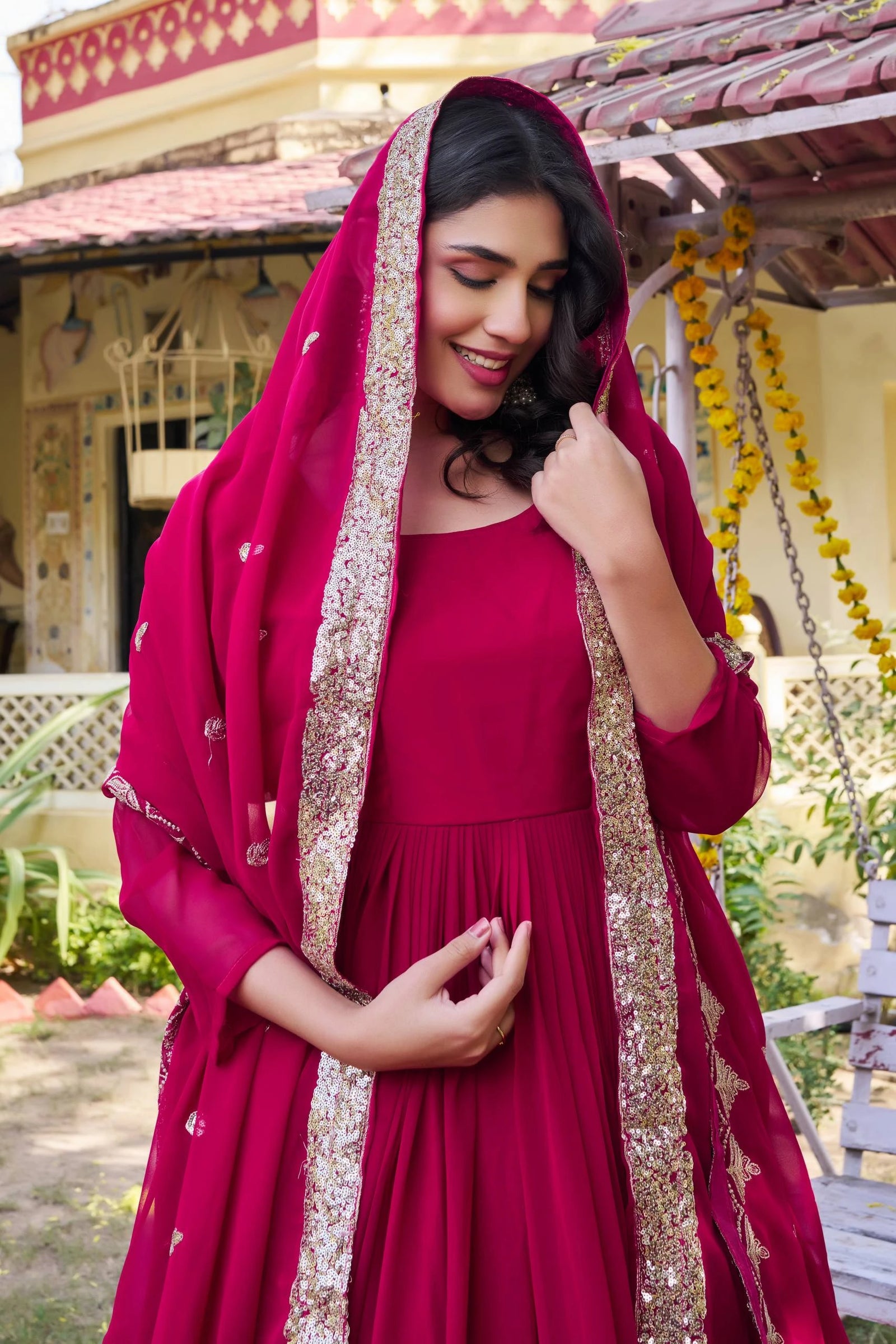 Woman in a red traditional outfit with a matching dupatta outdoors.