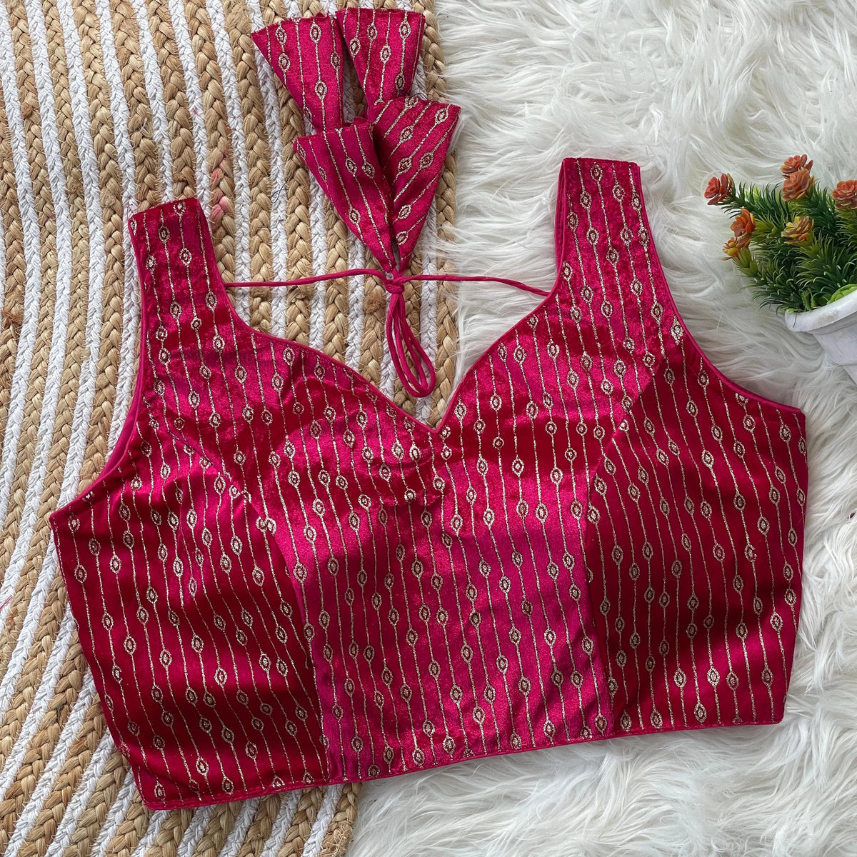 Red patterned top on a textured surface with a small plant in the corner.