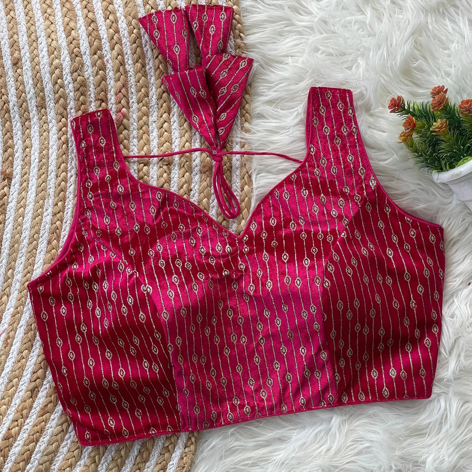 Red patterned top on a textured surface with a small plant in the corner.