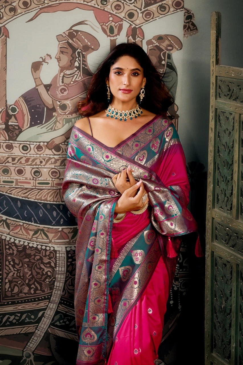 Woman in a traditional saree standing in front of an ornate wall mural.