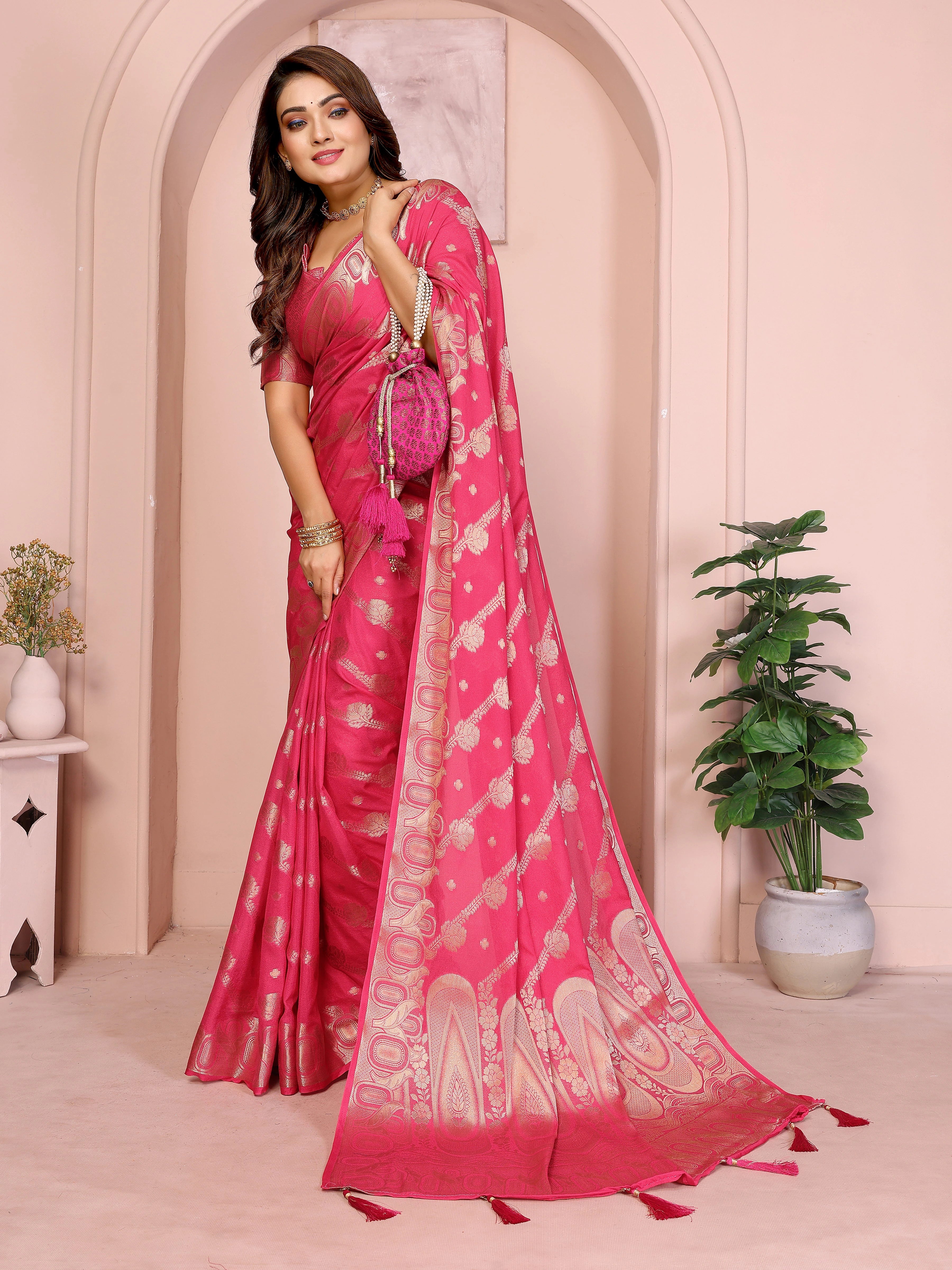 Woman wearing a pink saree with a white border in an indoor setting.
