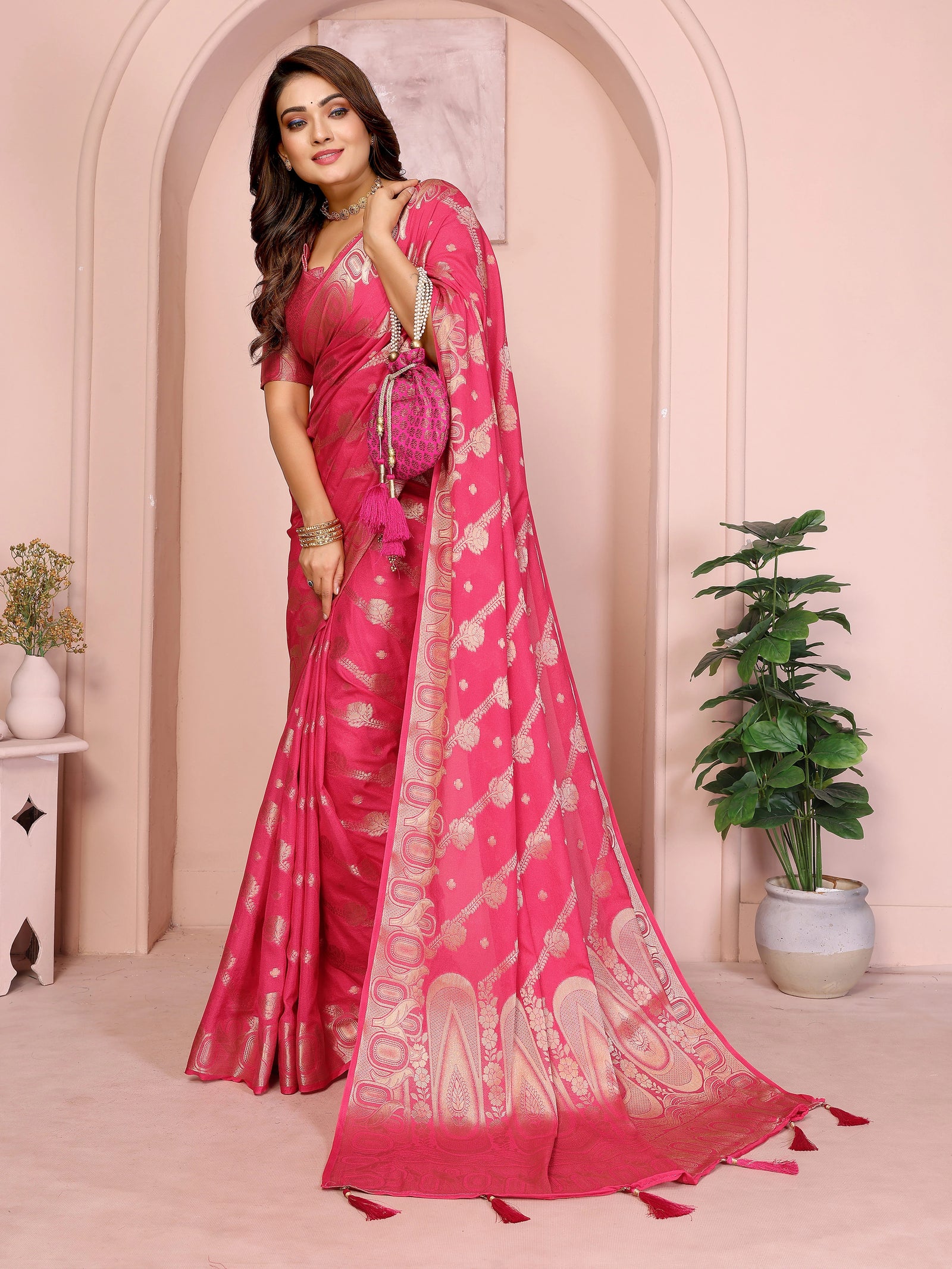Woman wearing a pink saree with a white border in an indoor setting.