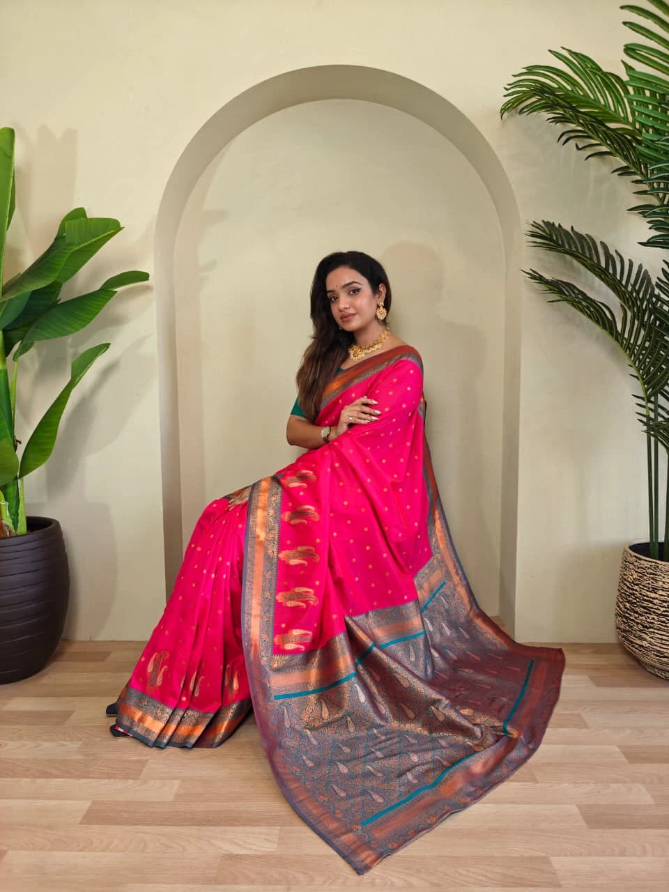 Woman in a pink saree standing in a room with plants