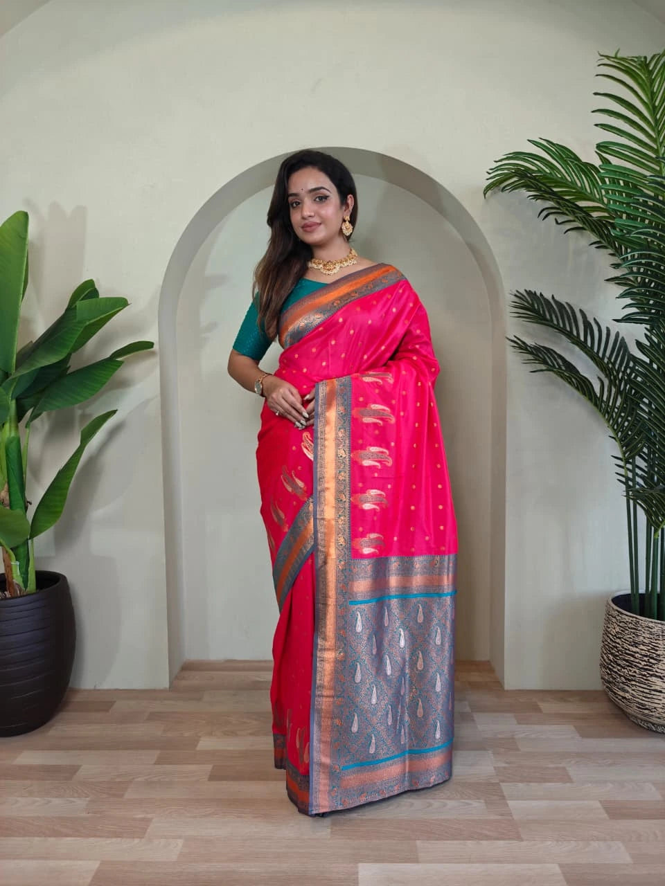 Woman in a pink saree standing in a room with plants
