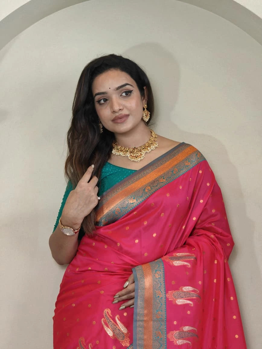 Woman wearing a pink saree with a green blouse against a plain background