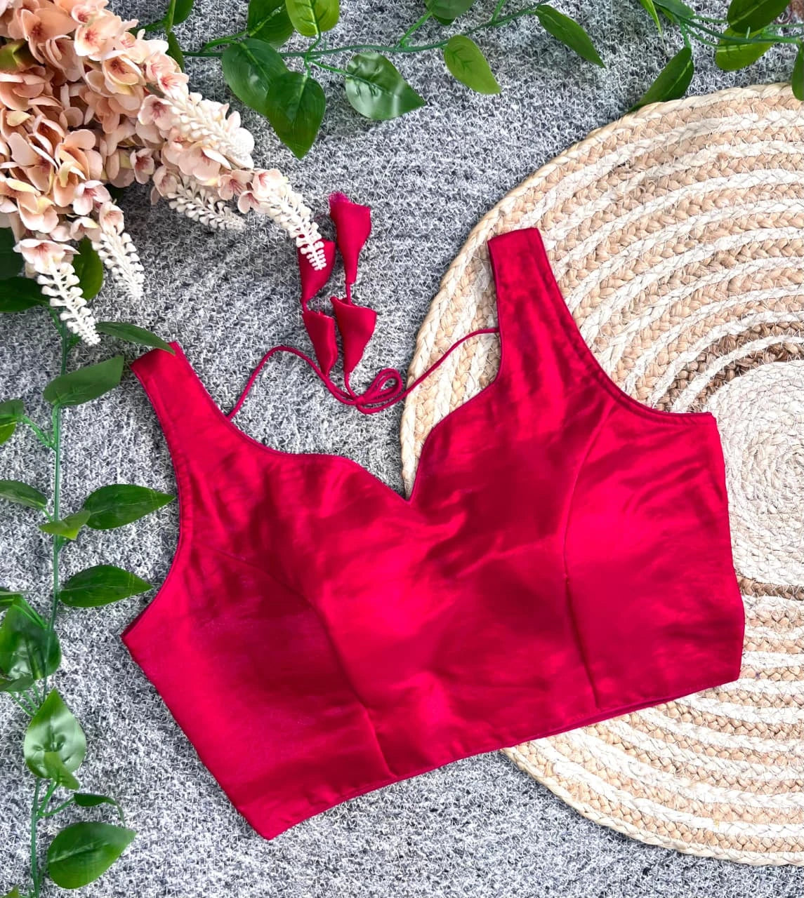 Red satin top on a textured surface with flowers and leaves