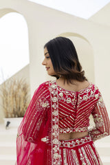 Woman wearing a red traditional outfit with intricate gold embroidery in an outdoor setting.