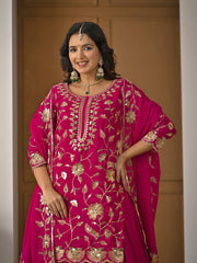 Woman wearing a pink embroidered traditional outfit with gold details against a plain background
