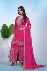 Woman wearing a pink traditional outfit with intricate designs on a light blue background